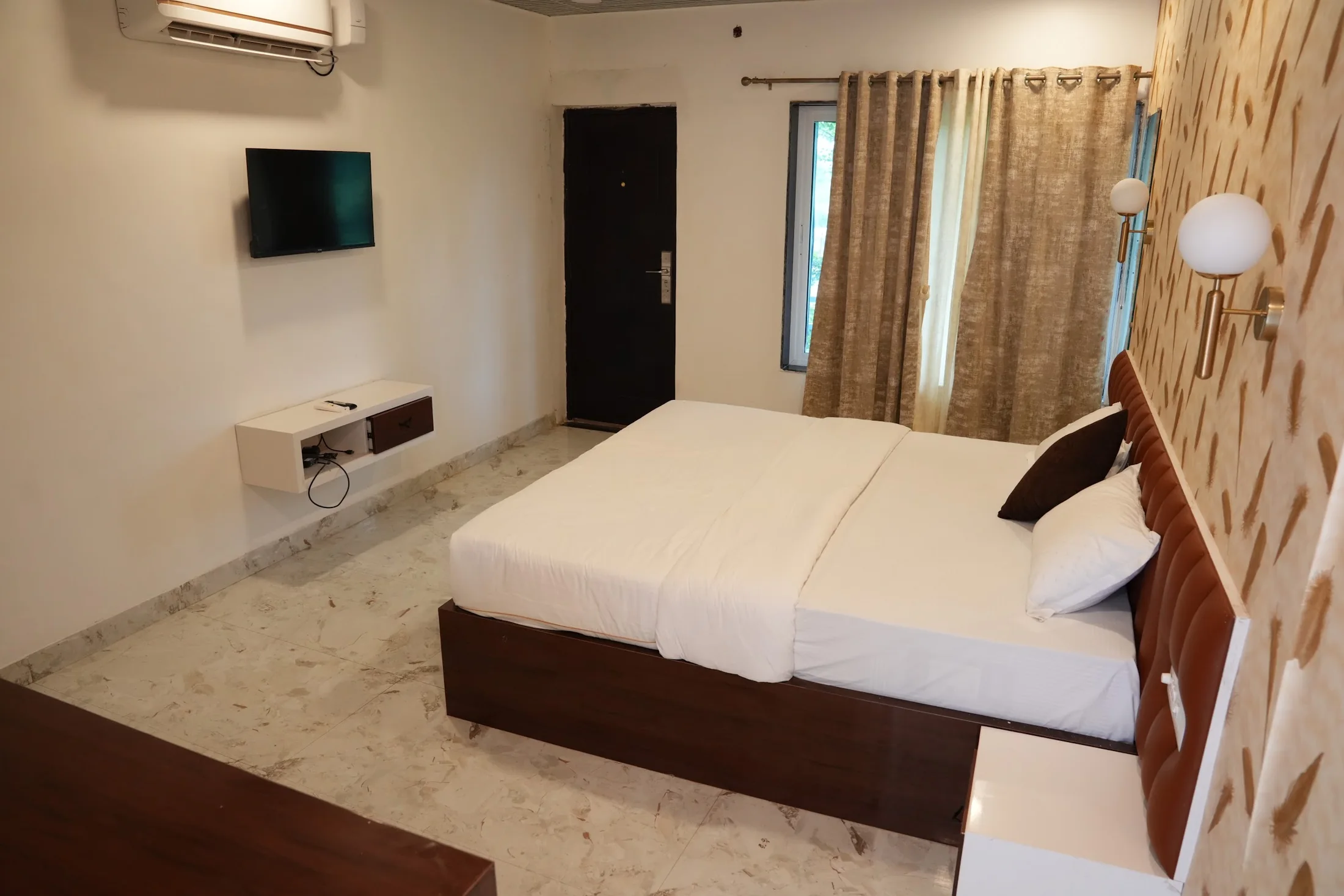 Deluxe room complete view at DS Agro Tourism & Resort. Bed, television, desk and entrance visible in one frame.