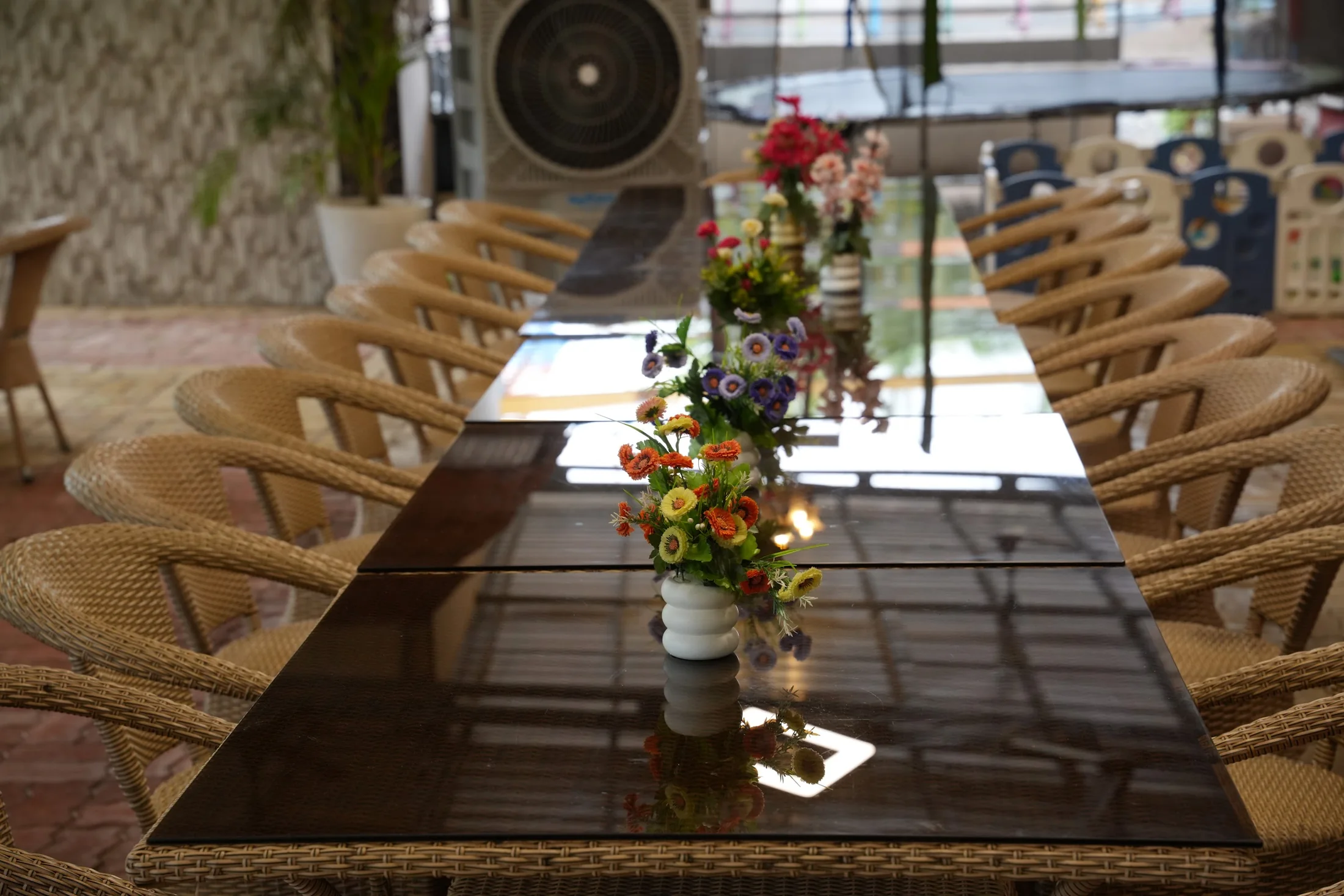 Table details at DS Agro Tourism & Resort. Flower arrangements and seating along a dining table.