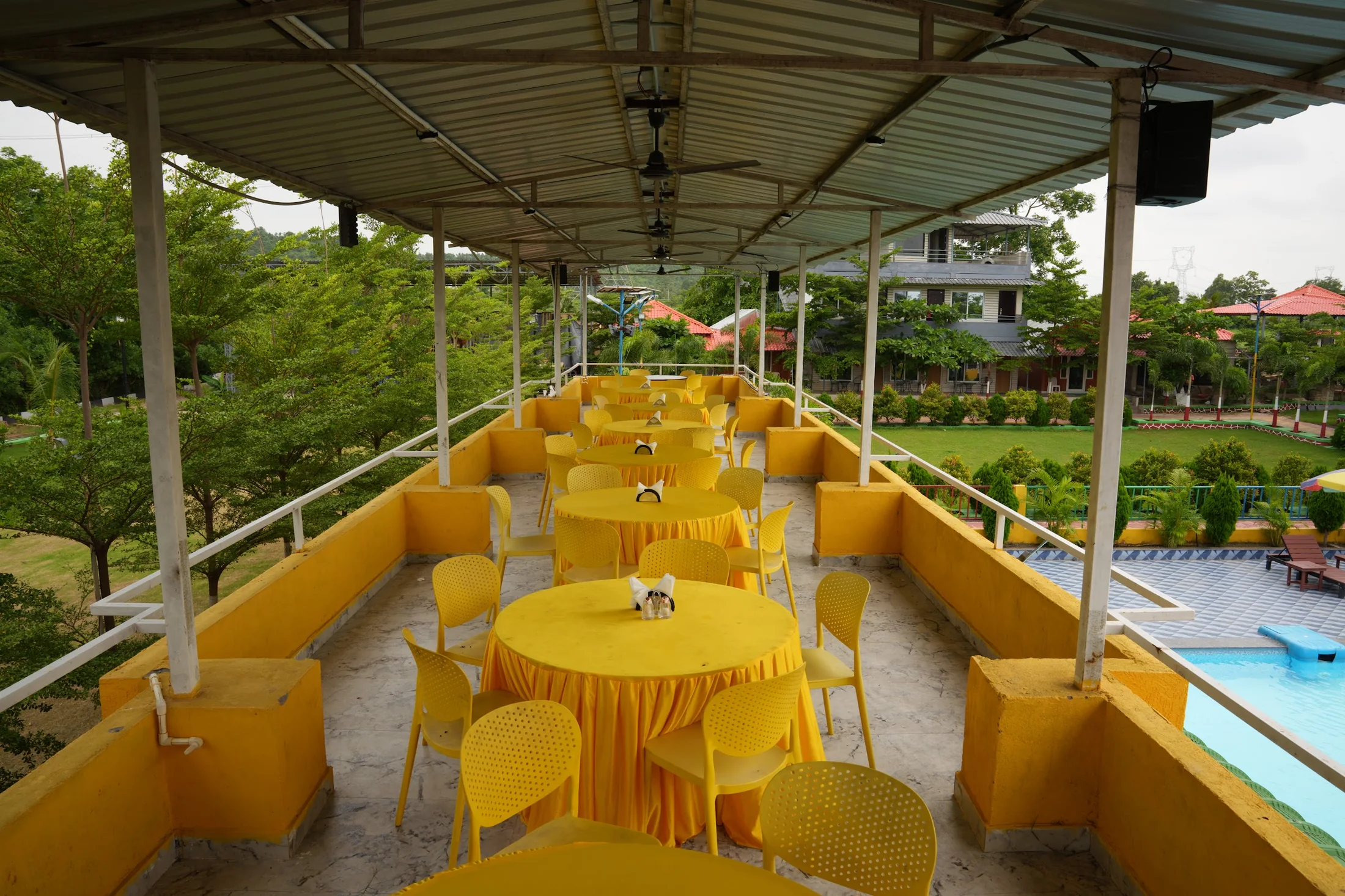 Poolside dining terrace at DS Agro Tourism & Resort. A covered table setup overlooking the main pool.
