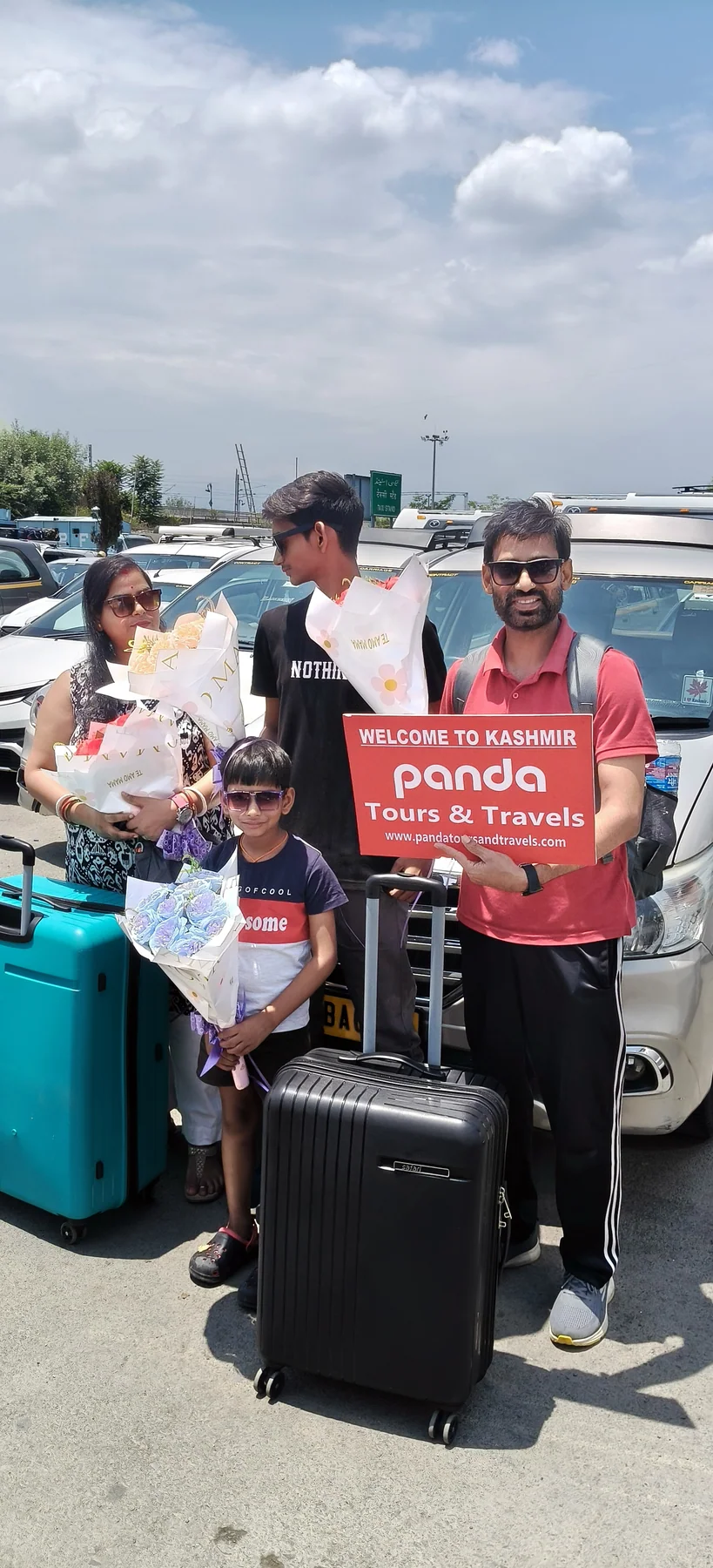 A family greeted at Srinagar airport with flowers and a welcome sign